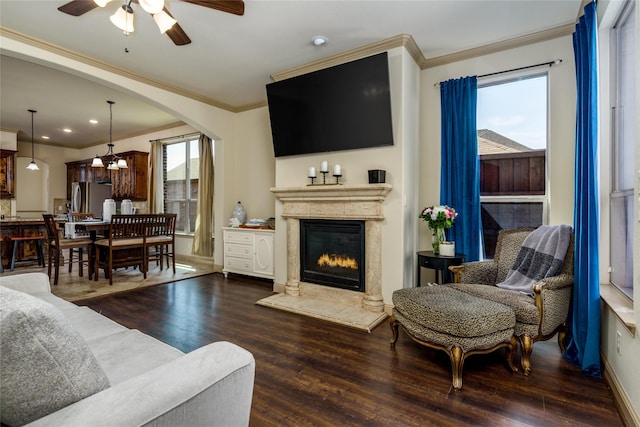 681 Harper Dr, Fate, TX 75087 - living room featuring a glass covered fireplace, wood finished floors, ornamental molding, ceiling fan, and arched walkways