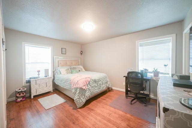 bedroom with baseboards, light wood-style flooring, and a textured ceiling