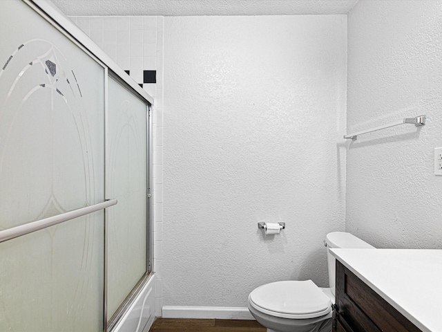 175 Clover Ln, Decatur, TX 76234 - bathroom with bath / shower combo with glass door, toilet, wood finished floors, vanity, and a textured wall