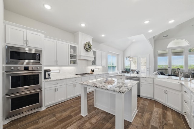 kitchen featuring white cabinetry, a sink, vaulted ceiling, and appliances with stainless steel finishes