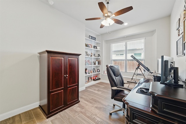 home office featuring baseboards, light wood-style flooring, built in features, and a ceiling fan