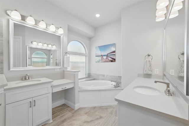 bathroom featuring two vanities, a sink, and a garden tub