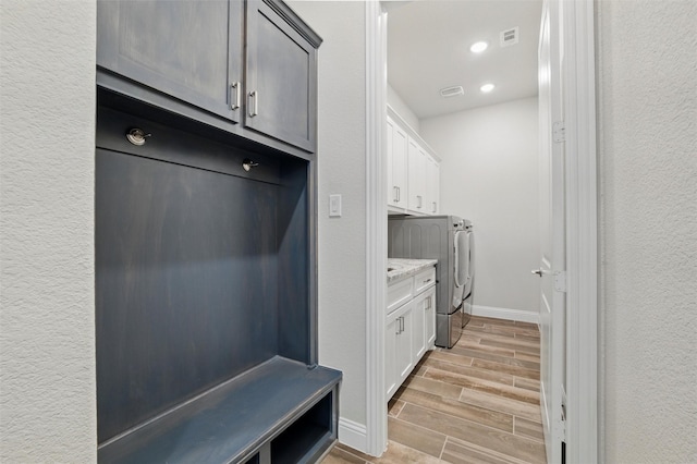 laundry room with baseboards, recessed lighting, wood tiled floor, washer and dryer, and cabinet space