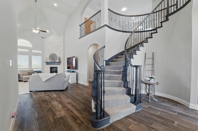 staircase featuring baseboards, high vaulted ceiling, wood finished floors, and ceiling fan