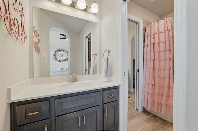 full bath with a shower with shower curtain, wood finished floors, and vanity