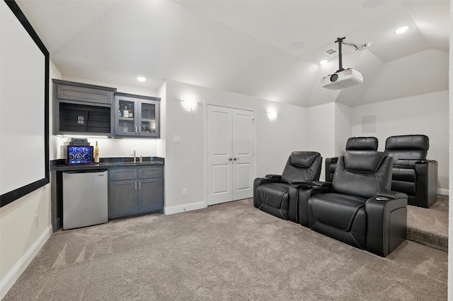 home theater featuring vaulted ceiling, baseboards, a sink, light carpet, and indoor wet bar