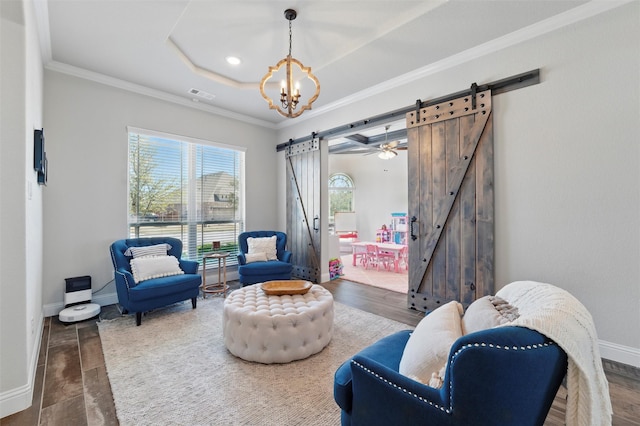 sitting room featuring baseboards, ornamental molding, wood finished floors, a raised ceiling, and a barn door