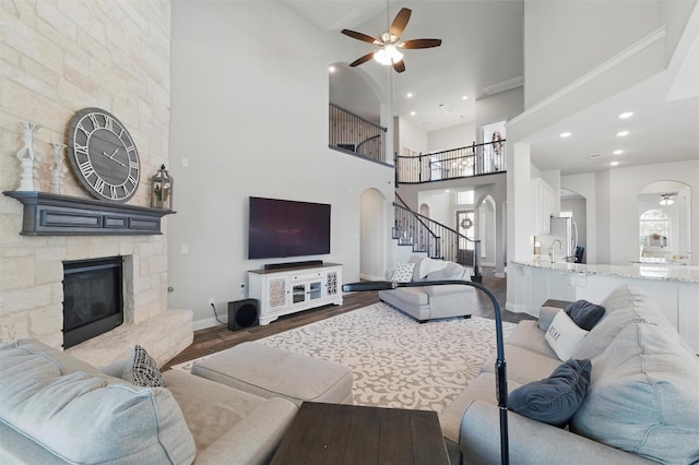 living area featuring a high ceiling, wood finished floors, baseboards, arched walkways, and ceiling fan