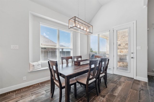 dining space with wood tiled floor, a wealth of natural light, lofted ceiling, and an inviting chandelier