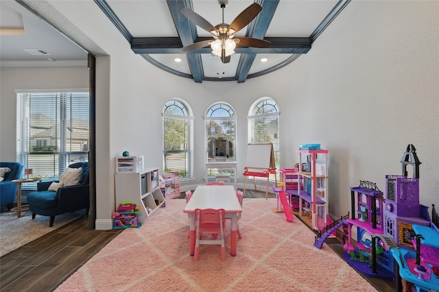 recreation room featuring a ceiling fan, a healthy amount of sunlight, beamed ceiling, and wood finished floors