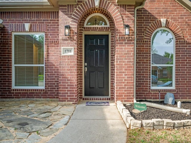 view of exterior entry featuring brick siding