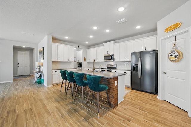 6028 Bowie Ct, Providence Village, TX 76227 - kitchen with appliances with stainless steel finishes, a sink, a kitchen breakfast bar, light wood-style floors, and recessed lighting