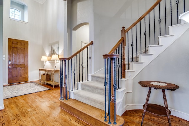 foyer entrance with baseboards, stairs, a towering ceiling, and wood finished floors