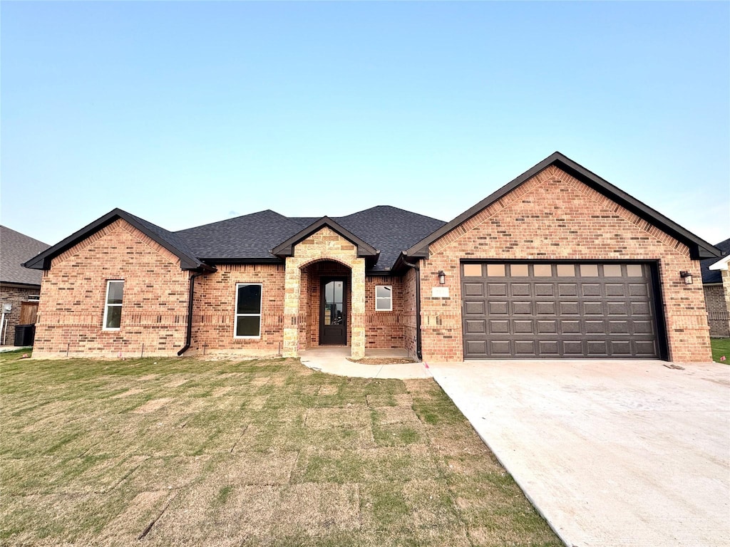 717 Cobblestone Cir, Mabank, TX 75147 - french country style house with brick siding, concrete driveway, a garage, and a front yard
