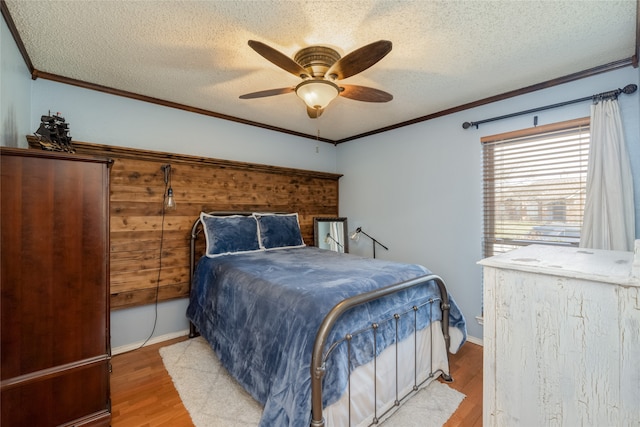 bedroom with a ceiling fan, ornamental molding, a textured ceiling, and wood finished floors