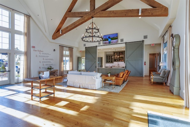1916 Pelham Dr, Aubrey, TX 76227 - living area with high vaulted ceiling, a barn door, beam ceiling, wood finished floors, and a chandelier
