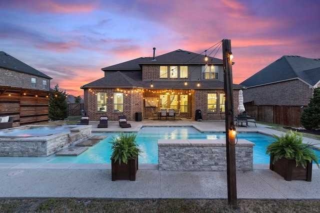 back of property at dusk featuring a fenced backyard, a patio, a pool with connected hot tub, and brick siding