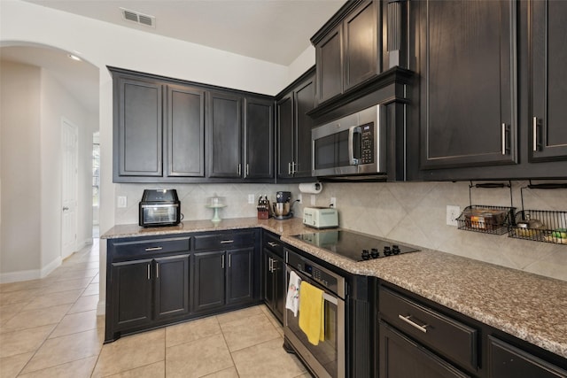 4600 Periwinkle Dr, Mansfield, TX 76063 - kitchen with stainless steel appliances, arched walkways, tasteful backsplash, light tile patterned floors, and baseboards