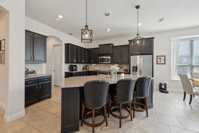 4600 Periwinkle Dr, Mansfield, TX 76063 - kitchen featuring appliances with stainless steel finishes, tasteful backsplash, light stone counters, a center island with sink, and recessed lighting