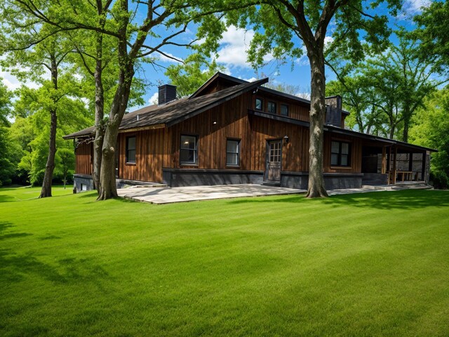 rear view of house featuring a lawn, a chimney, and a patio area