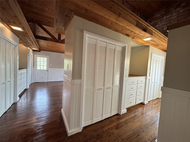 hall with dark wood-type flooring, wainscoting, beam ceiling, and wood ceiling