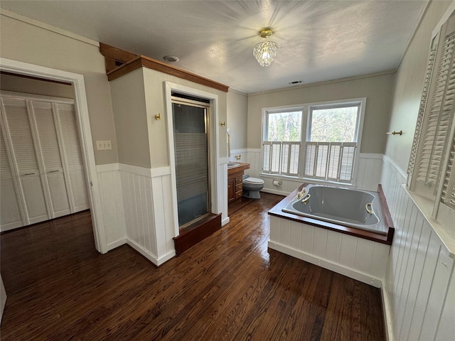 full bath featuring wainscoting, wood finished floors, toilet, a bath, and a stall shower
