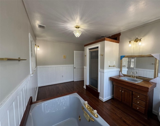 full bath featuring vanity, a garden tub, wainscoting, and wood finished floors