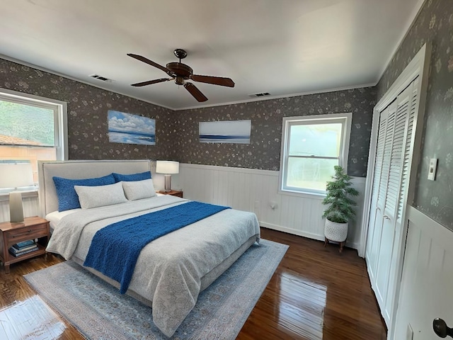 bedroom featuring wainscoting, visible vents, and multiple windows