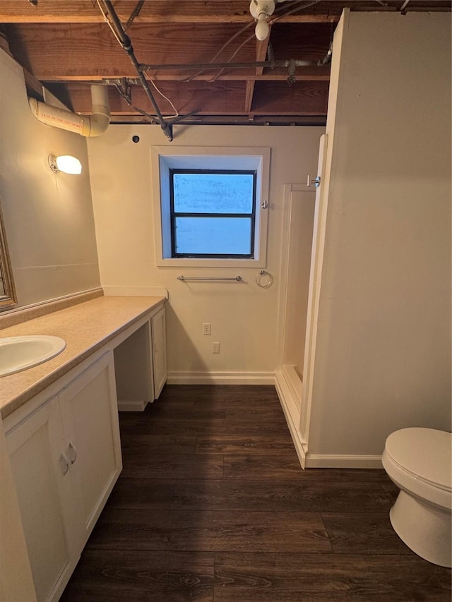 bathroom featuring vanity, baseboards, wood finished floors, and toilet