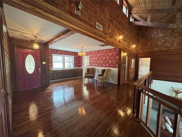entryway featuring an inviting chandelier, beam ceiling, wood finished floors, and visible vents