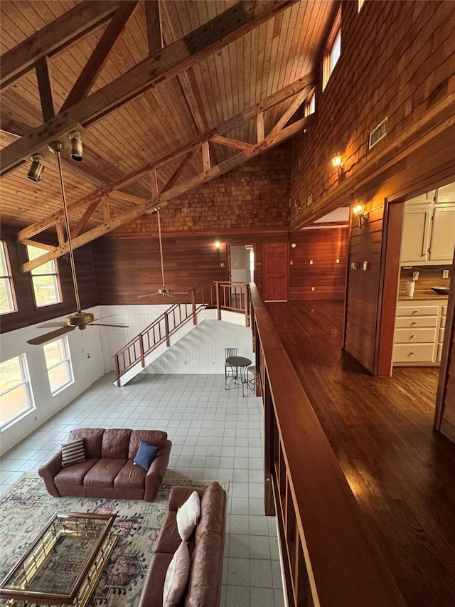 interior space featuring wooden walls, high vaulted ceiling, a ceiling fan, wooden ceiling, and visible vents