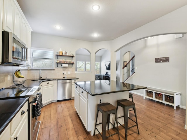 4013 Hollow Lake Rd, Fort Worth, TX 76262 - kitchen featuring stainless steel appliances, a sink, dark countertops, a kitchen breakfast bar, and white cabinetry