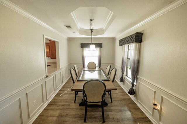 dining room featuring a decorative wall, visible vents, a raised ceiling, and dark wood-style floors