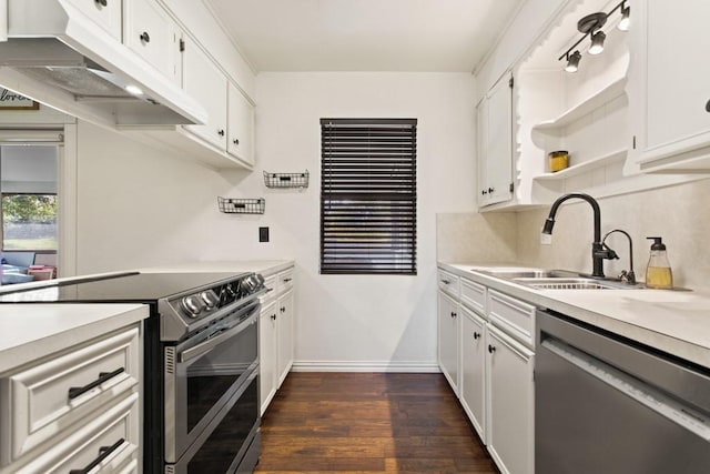 kitchen featuring light countertops, a sink, appliances with stainless steel finishes, under cabinet range hood, and dark wood-style flooring