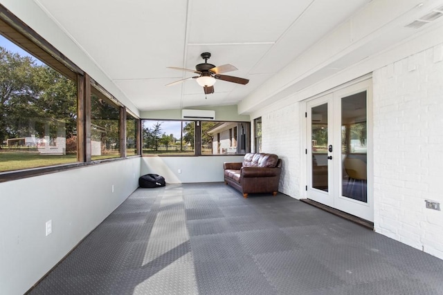 unfurnished sunroom featuring french doors, a wall unit AC, and ceiling fan