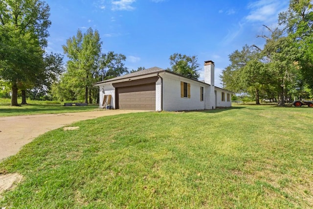 view of home's exterior with driveway, a chimney, brick siding, a lawn, and a garage