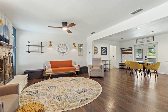living area featuring dark wood-type flooring, visible vents, and a ceiling fan