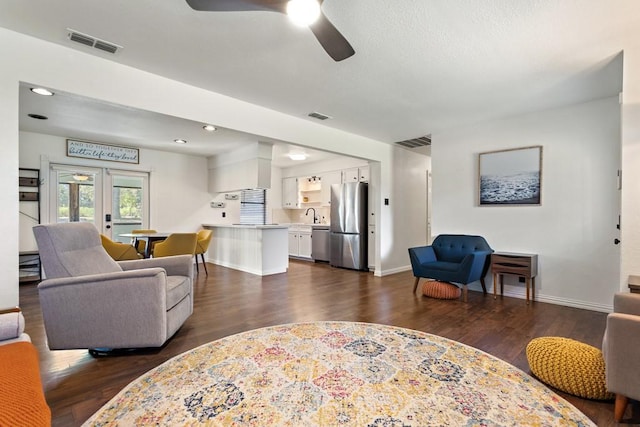 living area with baseboards, dark wood-style floors, ceiling fan, and visible vents