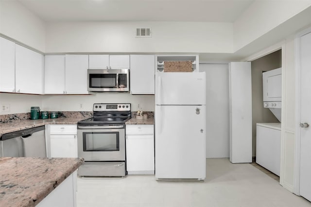 1700 Amelia Ct Unit 312, Plano, TX 75075 - kitchen with stainless steel appliances, estacked washer and dryer, white cabinets, and light stone counters