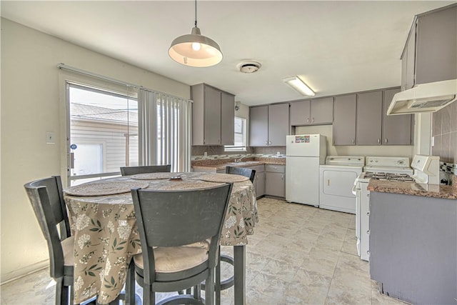 kitchen featuring gray cabinets, a sink, washing machine and clothes dryer, white appliances, and visible vents