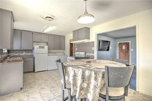 kitchen with tasteful backsplash, white appliances, independent washer and dryer, gray cabinetry, and a sink