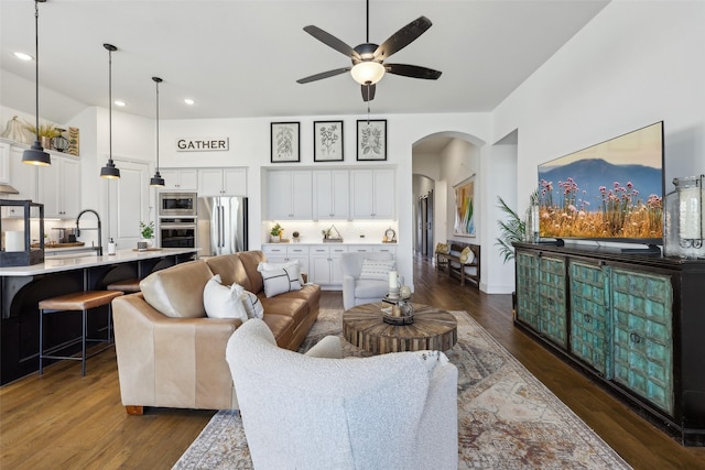 living room featuring arched walkways, ceiling fan, recessed lighting, and dark wood-style flooring