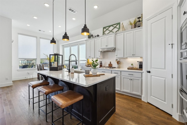 kitchen with white cabinetry, tasteful backsplash, stainless steel gas cooktop, a sink, and visible vents