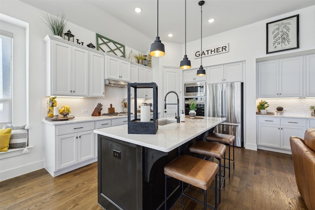 kitchen featuring dark wood-type flooring, white cabinetry, a breakfast bar, and stainless steel appliances