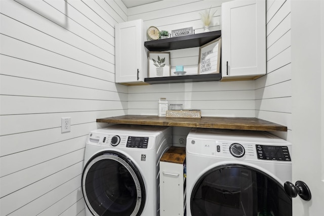 washroom with washing machine and dryer, wood walls, and cabinet space