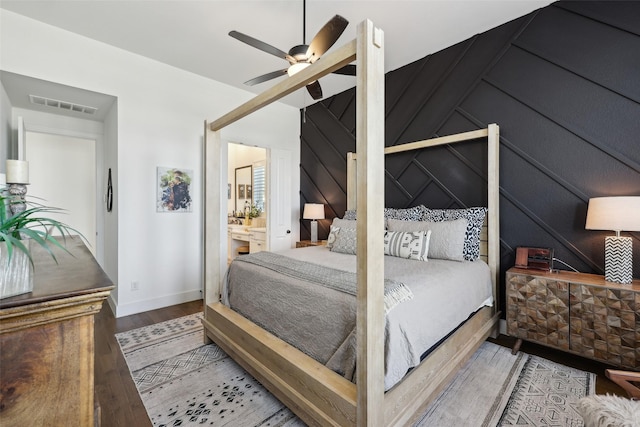 bedroom featuring wood finished floors, ensuite bathroom, ceiling fan, and visible vents