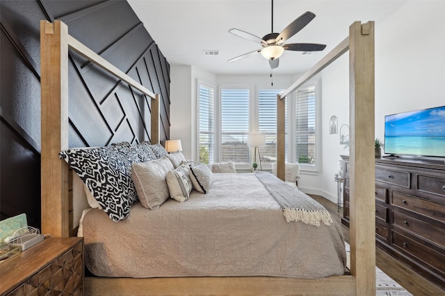 bedroom featuring baseboards, visible vents, wood finished floors, and a ceiling fan