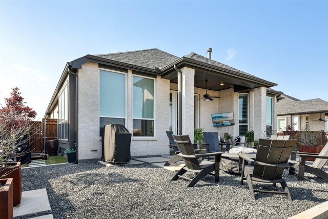 rear view of property with fence, a ceiling fan, brick siding, roof with shingles, and a patio area