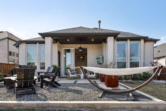 rear view of house featuring roof with shingles, fence, ceiling fan, brick siding, and a patio area