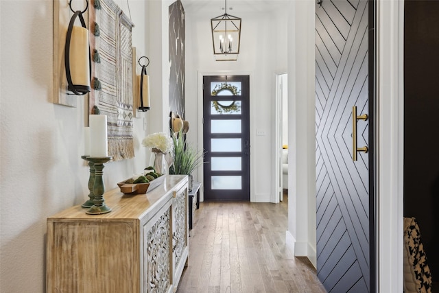 foyer entrance with baseboards, wood finished floors, and a chandelier